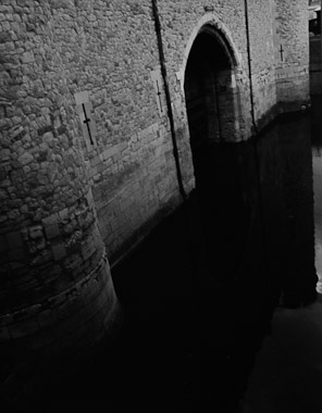 A black and white picture of the exterior of Traitor's Gate at Tower of London with the moat in front.