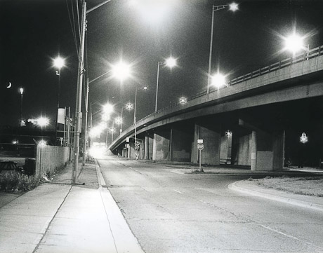 A black and whit picture of the Burlington Street overpass at night with street light stars.